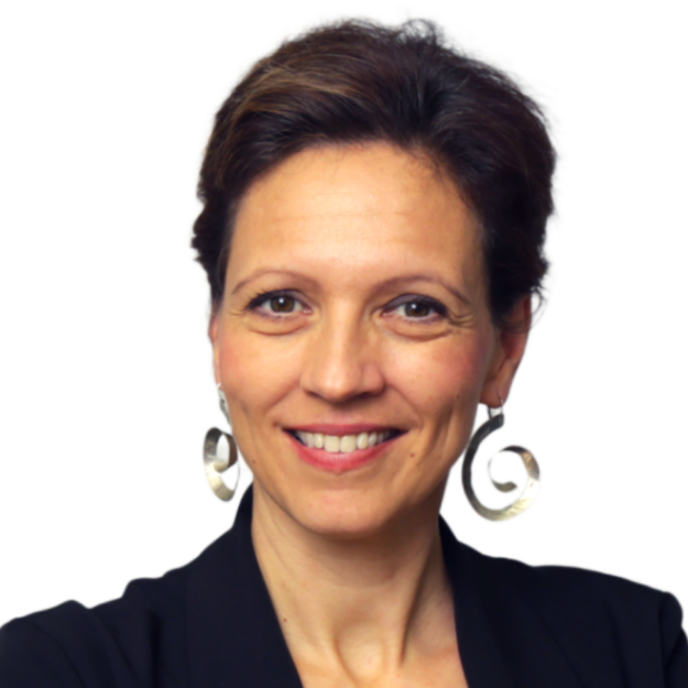 A woman with short brown hair is smiling at the camera. She is wearing large, spiral-shaped silver earrings and a dark blazer. The background is plain white.